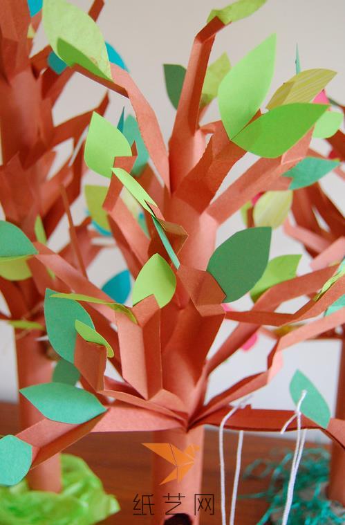 然后用绿色的彩纸剪成树叶的样子贴到树木上面
