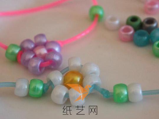 将塑料绳再从对面珠子中间串过，就可以将中间的珠子固定好了，两边可以再串上彩色的珠子，这样这条手链就制作好啦