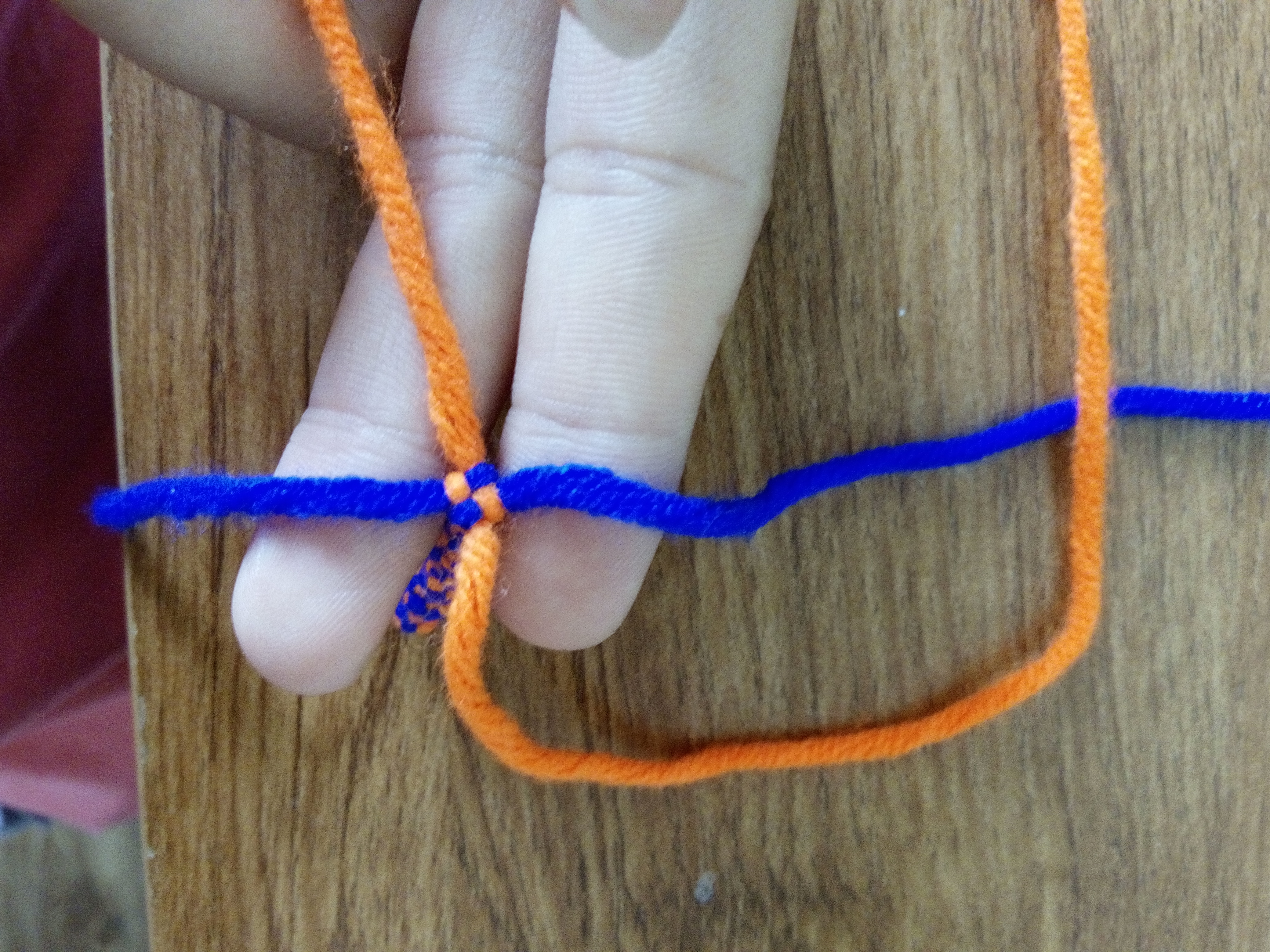 步骤二：下面橘色的线压右面蓝色的线。注意这个产生的环，下面还要用到它。